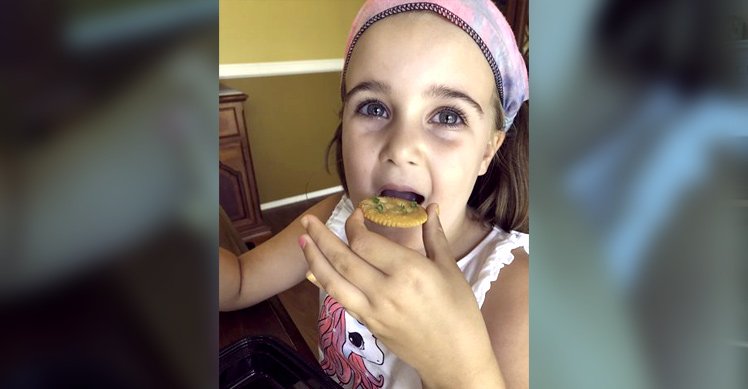 a little girl enjoys a snack of microgreens on crackers