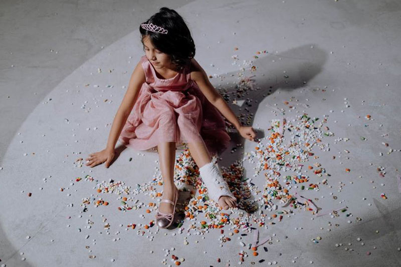 A girl in a pink dress and pink shoe wearing an ankle cast